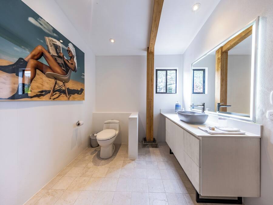 A modern bathroom with a large mirror, a sink, and a toilet.
