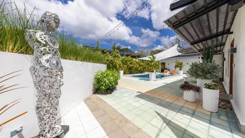 Une terrasse extérieure moderne, dotée d’une piscine, de plantes en pot et d’une sculpture métallique originale.