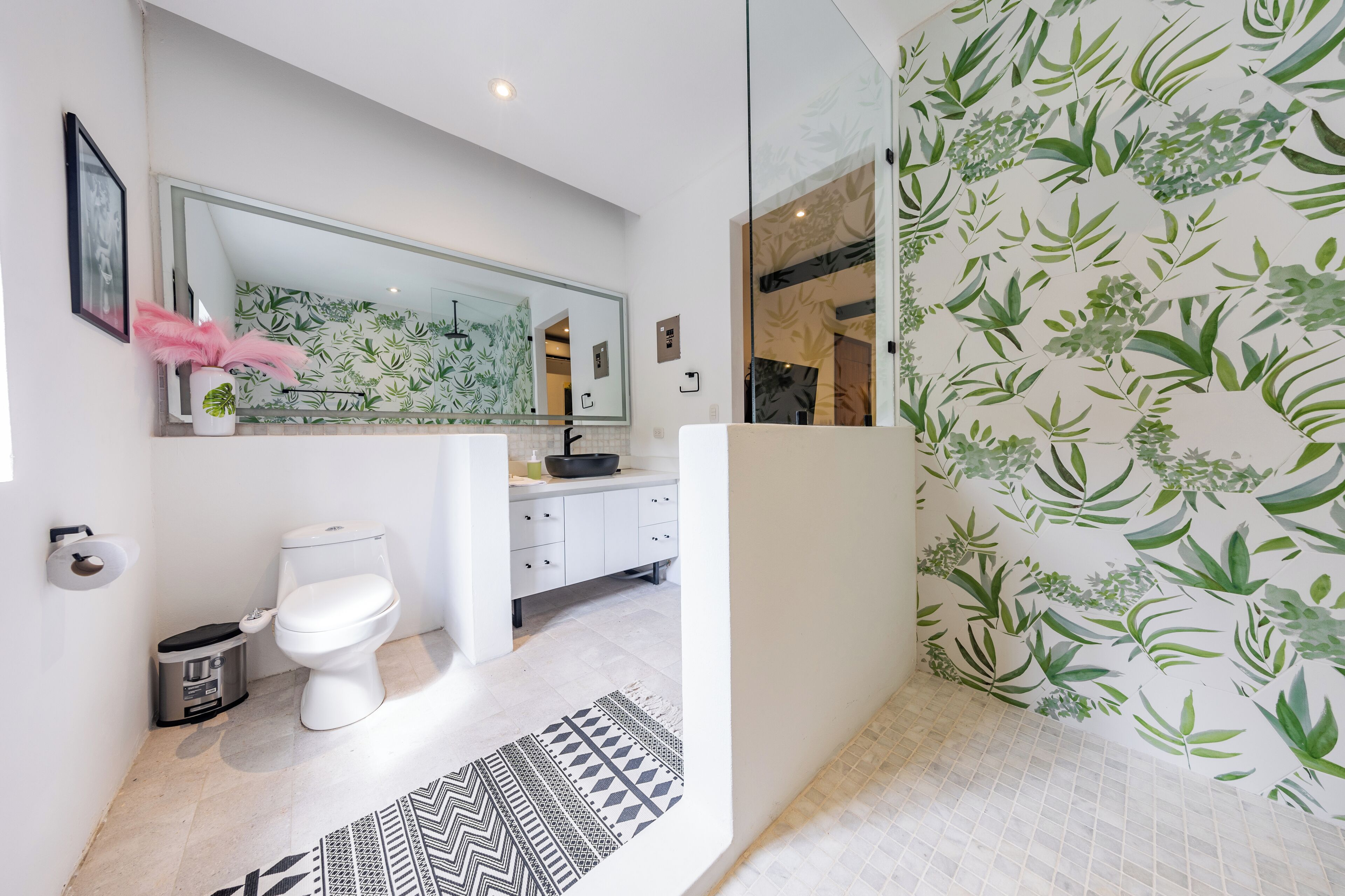 Un baño moderno con lavamanos blanco, inodoro y zona de ducha.
