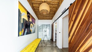 Un pasillo con techo de madera, un banco amarillo y un mural en la pared.