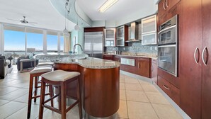 A modern kitchen with stainless steel appliances, a bar area, and large windows offering a view.