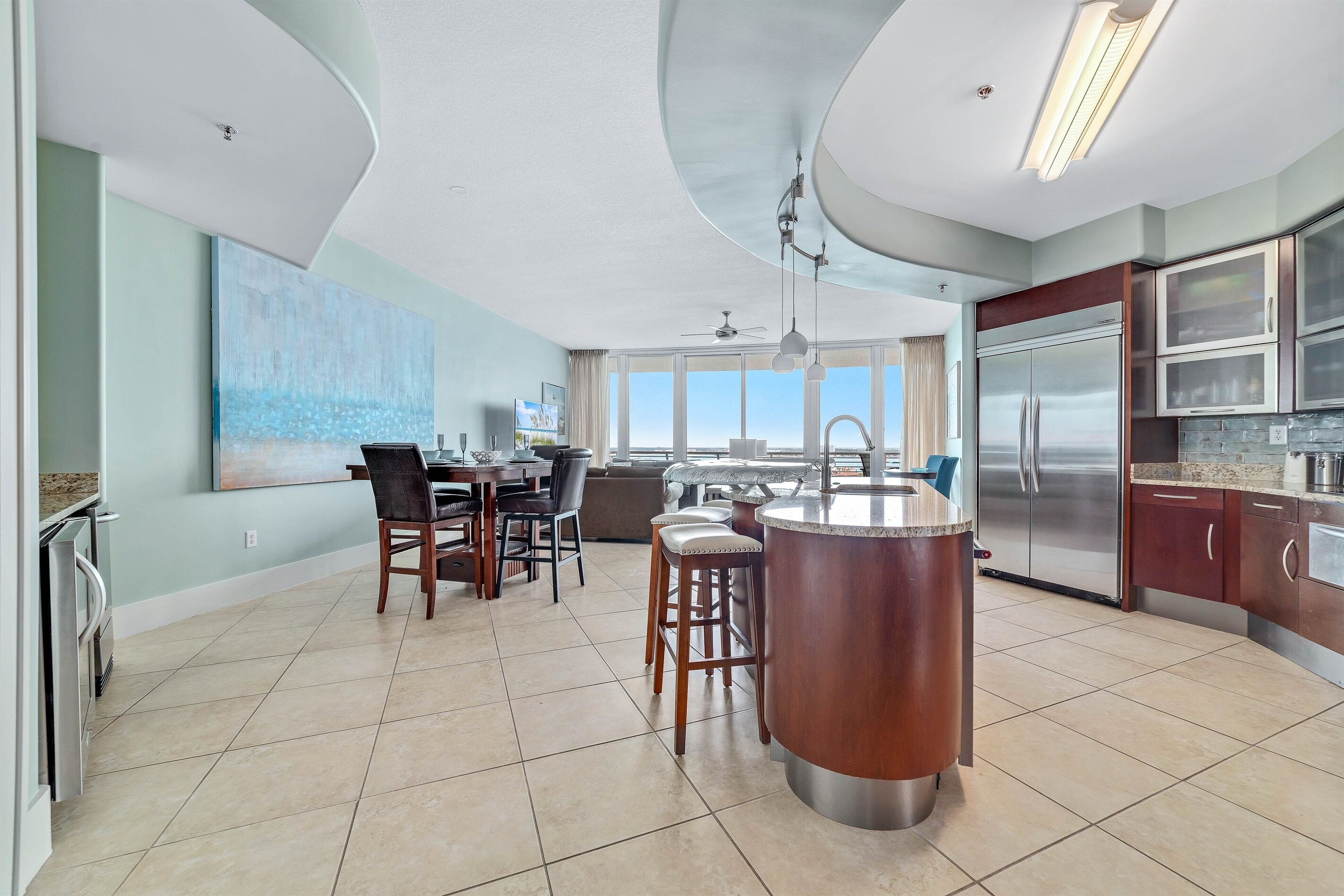 A modern kitchen with a central island, stainless steel appliances, and a dining area with chairs and a table.