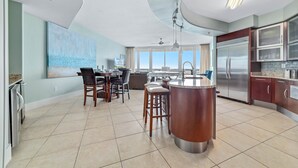 A modern kitchen with a central island, stainless steel appliances, and a dining area with chairs and a table.