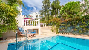 A swimming pool with lounge chairs, a staircase, and a view of a building with balconies.