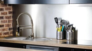 Una cocina moderna con un lavamanos de acero inoxidable, armarios negros y encimera de madera.