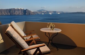 Ein Balkon mit zwei Liegestühlen und einem kleinen Tisch mit einer Vase getrockneter Pflanzen.