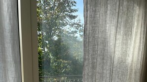 A view through a glass door with a metal railing, leading to an outdoor area with tiled flooring. - Elegant apartment, villa surrounded by greenery a stone's throw from the lake and the village (Garda)