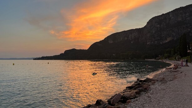 A coastal scene with a rocky shoreline, calm water, and a sunset. - Elegant apartment, villa surrounded by greenery a stone's throw from the lake and the village (Garda)