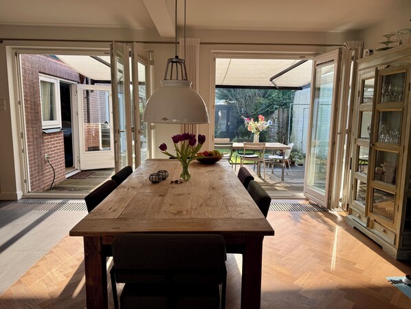 Enjoy meals in this dining area with a table, chairs, and a vase of flowers, offering a view of the outdoor patio and deck.