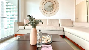 A modern living room with a sofa, a coffee table with a vase, a bottle, and a welcome sign. - w Impeccable 2BR w Charming Balcony in CTG (Cartagena)