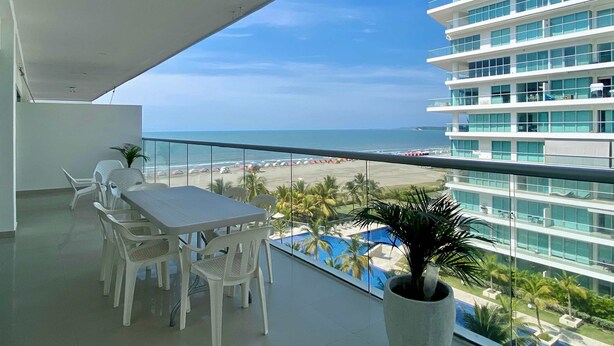 A balcony with a table and chairs, overlooking a beach and a pool. - w Impeccable 2BR w Charming Balcony in CTG (Cartagena)