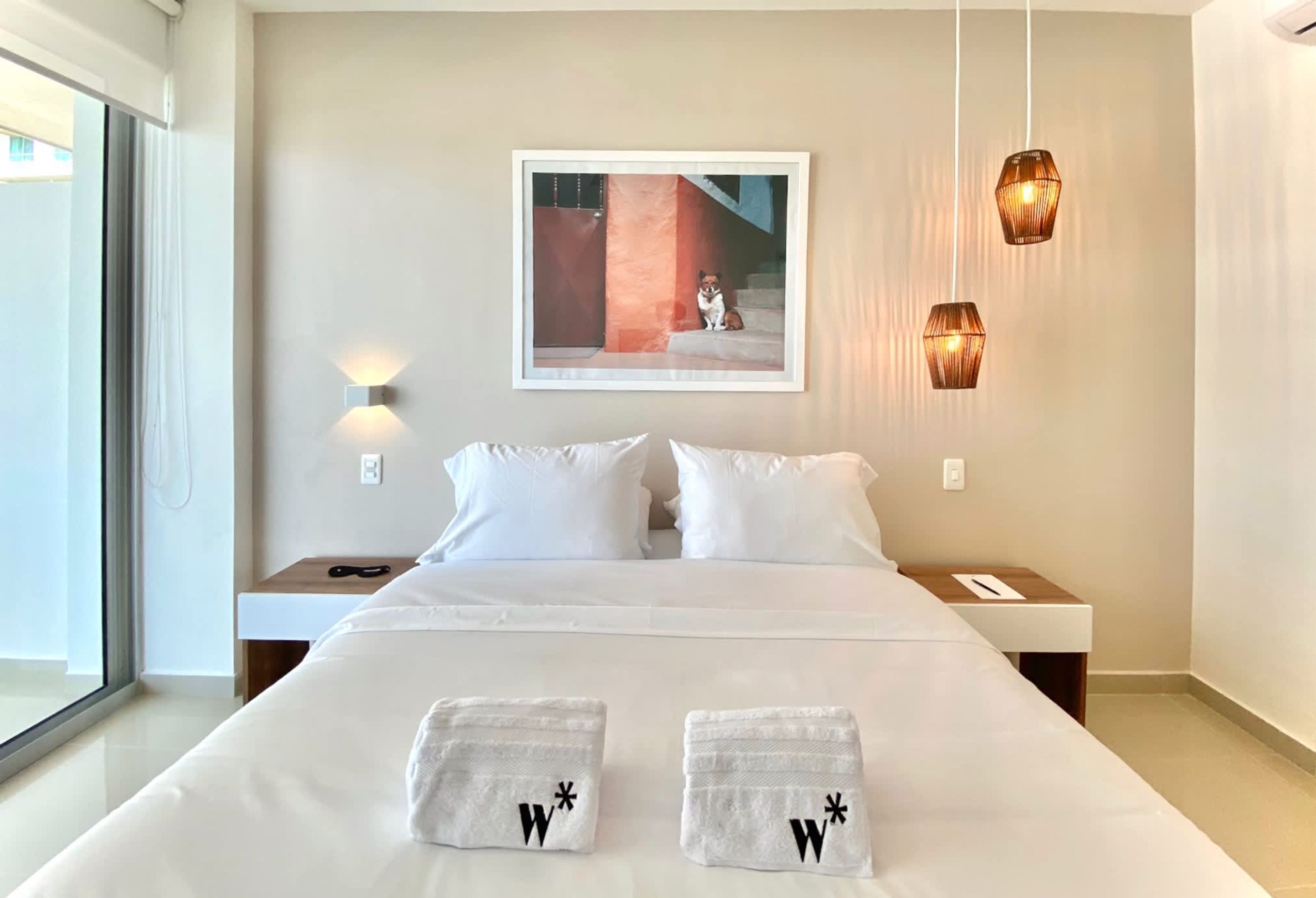 Une chambre d’hôtel avec un grand lit, deux oreillers blancs, un tableau encadré au mur et deux lampes de chevet.