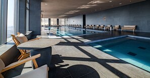 A modern indoor swimming pool with lounge chairs and a sunlit area. - Luxury Studio - Pool - Revolution Monument View (Mexico City)