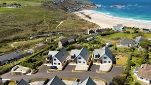 A coastal residential area with houses, a beach, and a lighthouse in the distance. - Family Beach House - Direct Access to Sennen Cove  Perfect for Summer Holidays (Sennen Cove)