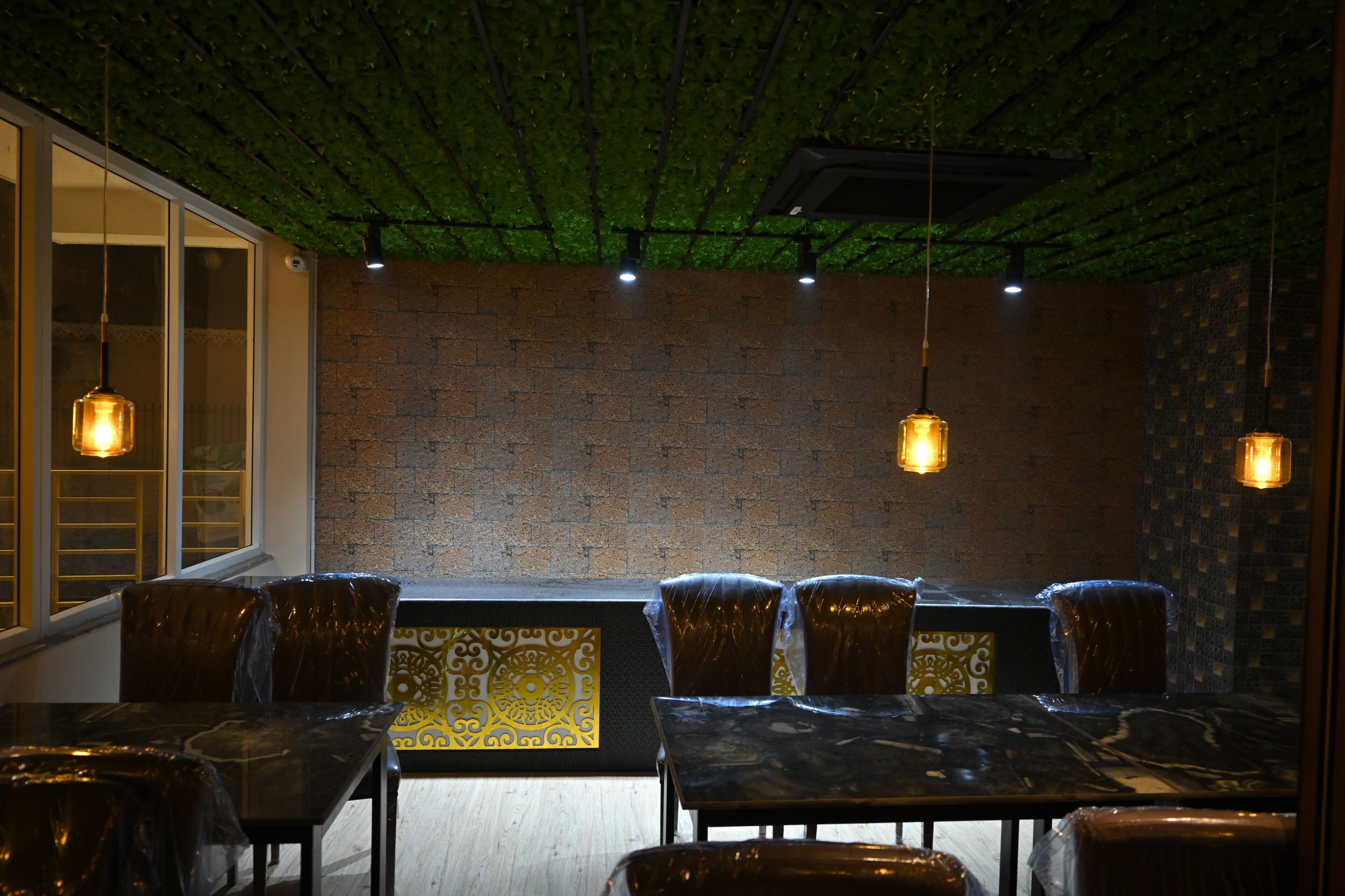 A restaurant with a brick wall, hanging pendant lights, and a patterned table runner.