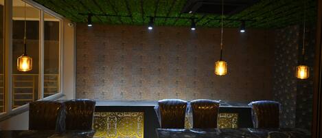 A restaurant with a brick wall, hanging pendant lights, and a patterned table runner.