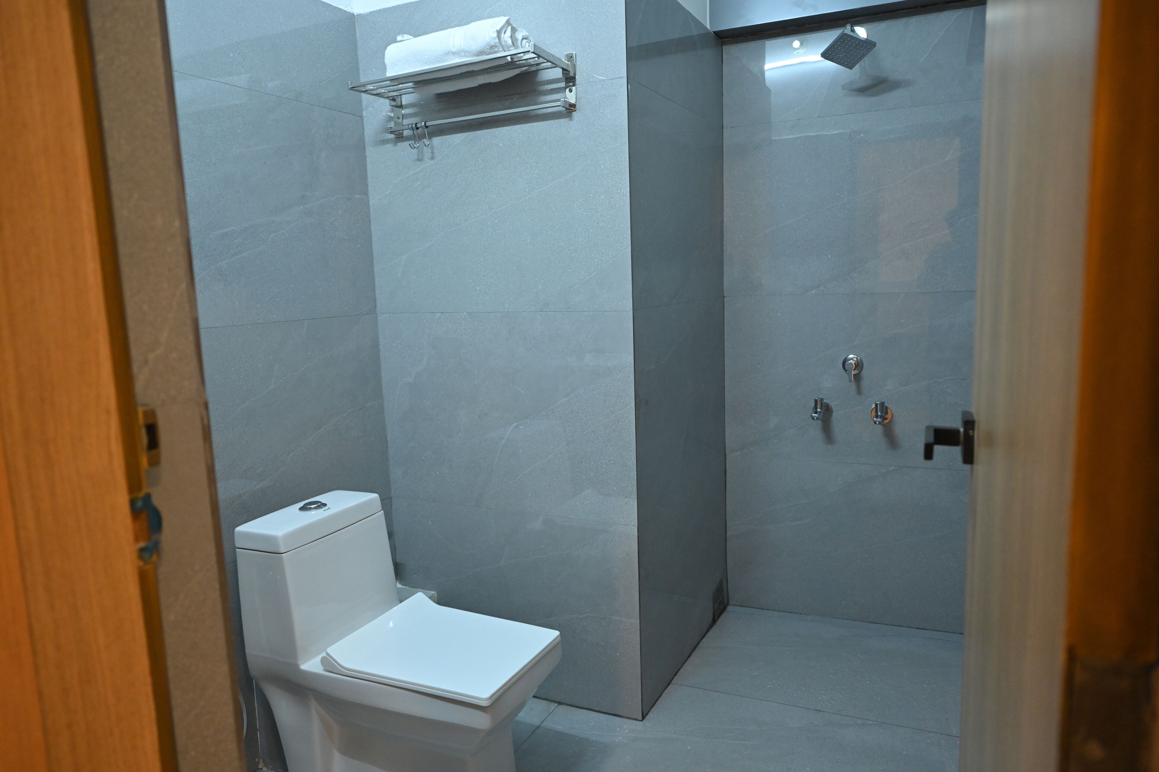 A modern bathroom with a toilet, a shower, and a towel rack.
