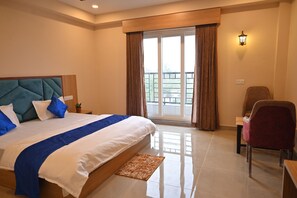 A bedroom with a large bed, a chair, a nightstand, and a window with curtains.