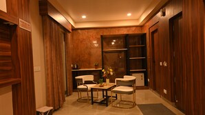 Habitación de hotel con piso de madera, una pequeña mesa con sillas, un escritorio y un armario.