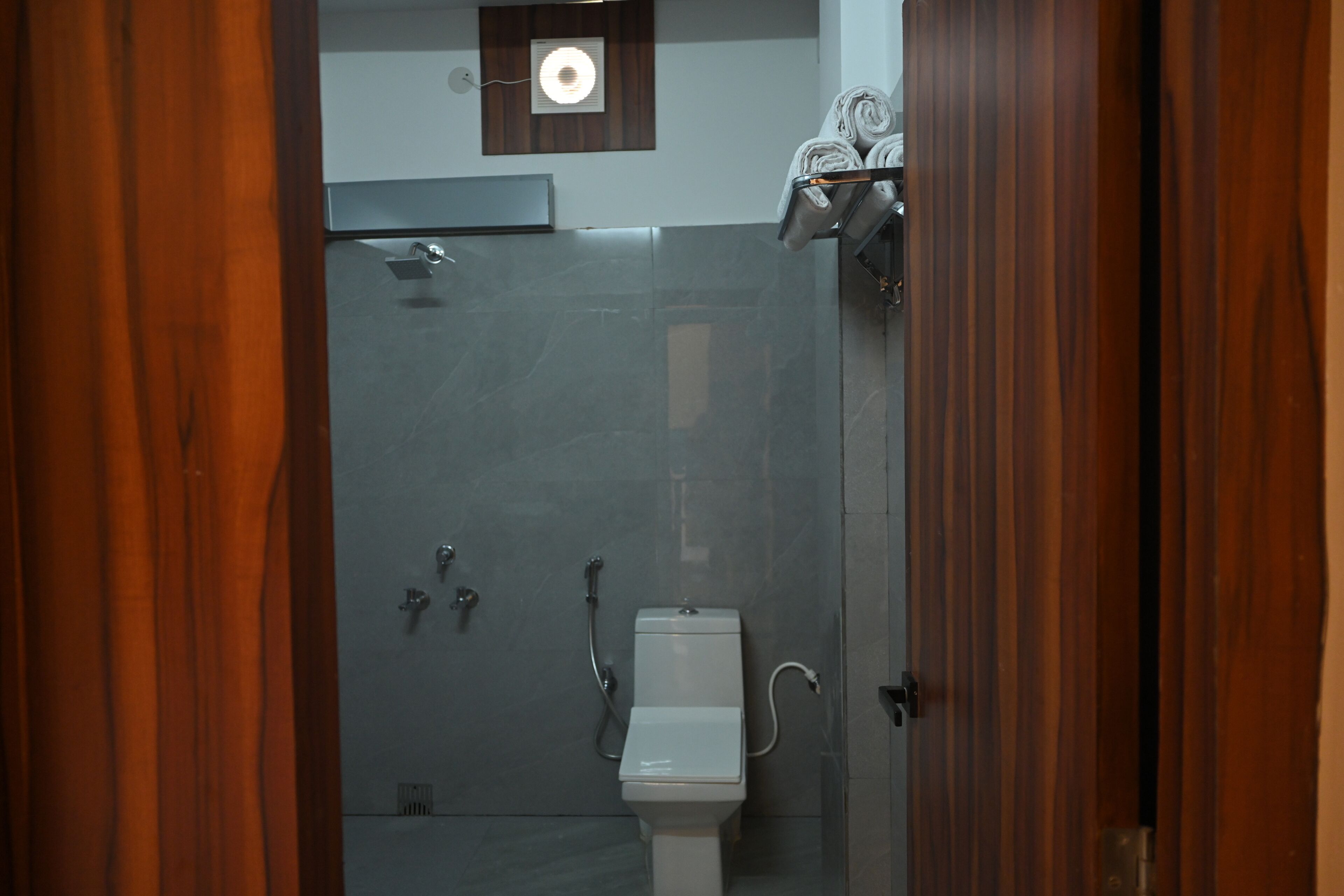 A bathroom with a toilet, shower, and towel rack.