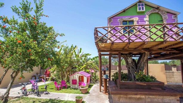 A colorful house with a balcony, a small playhouse, and a tree. - Laylande House with Private Pool (Theologos)