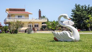 A swan sculpture on a lawn in front of a two-story building with a balcony. - Laylande House with Private Pool (Theologos)