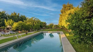 A rectangular swimming pool with a metal ladder, surrounded by well-maintained grass and trees. - Laylande House with Private Pool (Theologos)