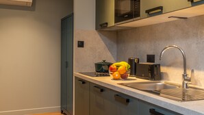 A modern kitchen with a stainless steel sink, a microwave, and a fruit bowl on the counter. - Montmartre Paris Suite (Paris)