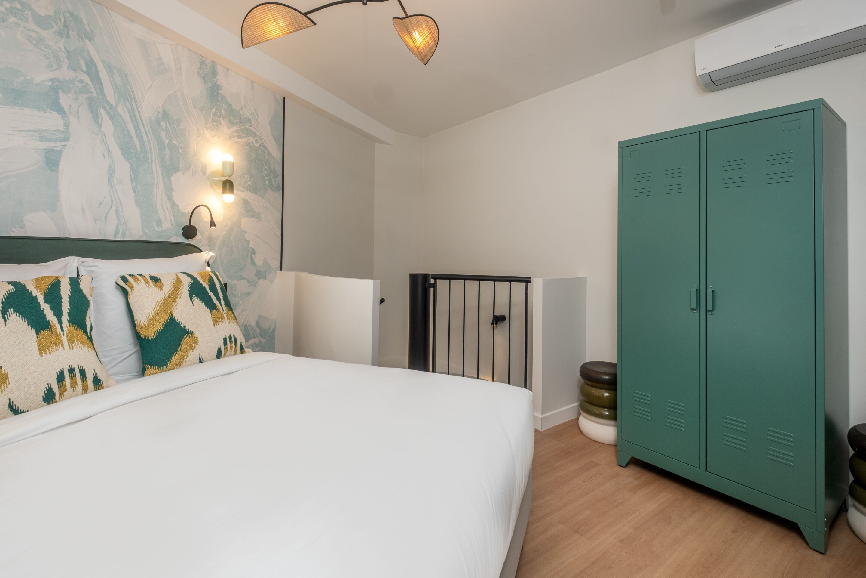 A bedroom with a bed, a wall-mounted light fixture, a green wardrobe, and a radiator.