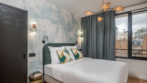 A bedroom with a bed, a wardrobe, a wall with a light fixture, and a window with curtains. - Montmartre Paris Suite (Paris)