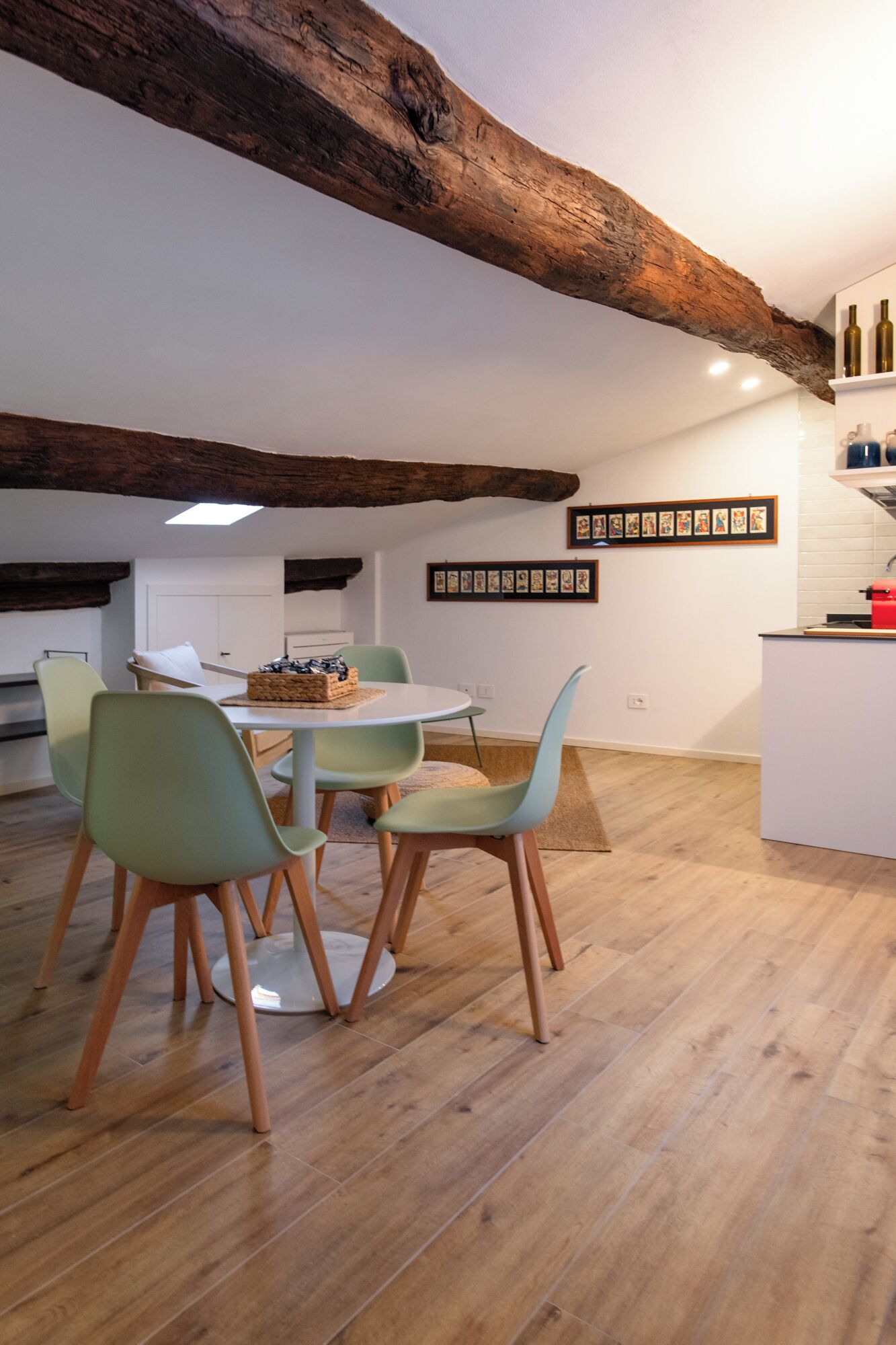 Un espace repas avec un plafond en bois, une table blanche et des chaises vert clair.
