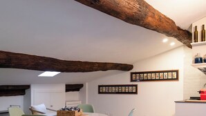 Un espace repas avec un plafond en bois, une table blanche et des chaises vert clair.
