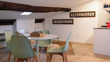 Un espace repas avec un plafond en bois, une table blanche et des chaises vert clair.