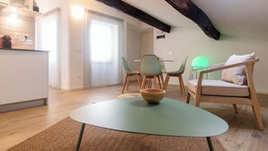 Une pièce chaleureuse avec une table ronde, une chaise verte, une chaise en bois et un lit avec un oreiller.