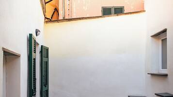 Un cortile con un tavolo e sedie, una piccola finestra e un cancello in metallo.