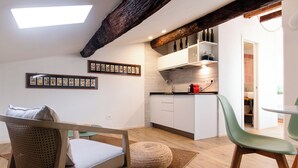 Une cuisine moderne avec des armoires blanches, un four encastré et un porte-bouteilles suspendu.