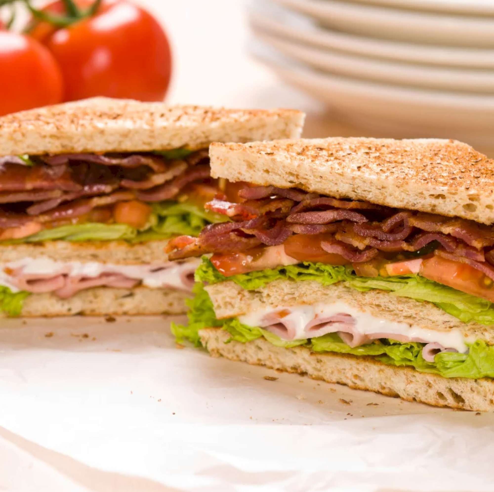 Un sandwich coupé en deux, révélant des couches de laitue, de tomate, de bacon et de fromage.