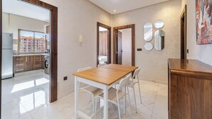 A modern kitchen with a wooden table and chairs, a view of the city through large windows, and a dining area with a wooden cabinet.