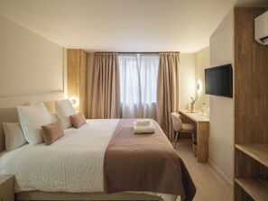 A hotel room with a bed, a desk, a chair, a TV, and a window with curtains. - Lits de lo (Ghent)
