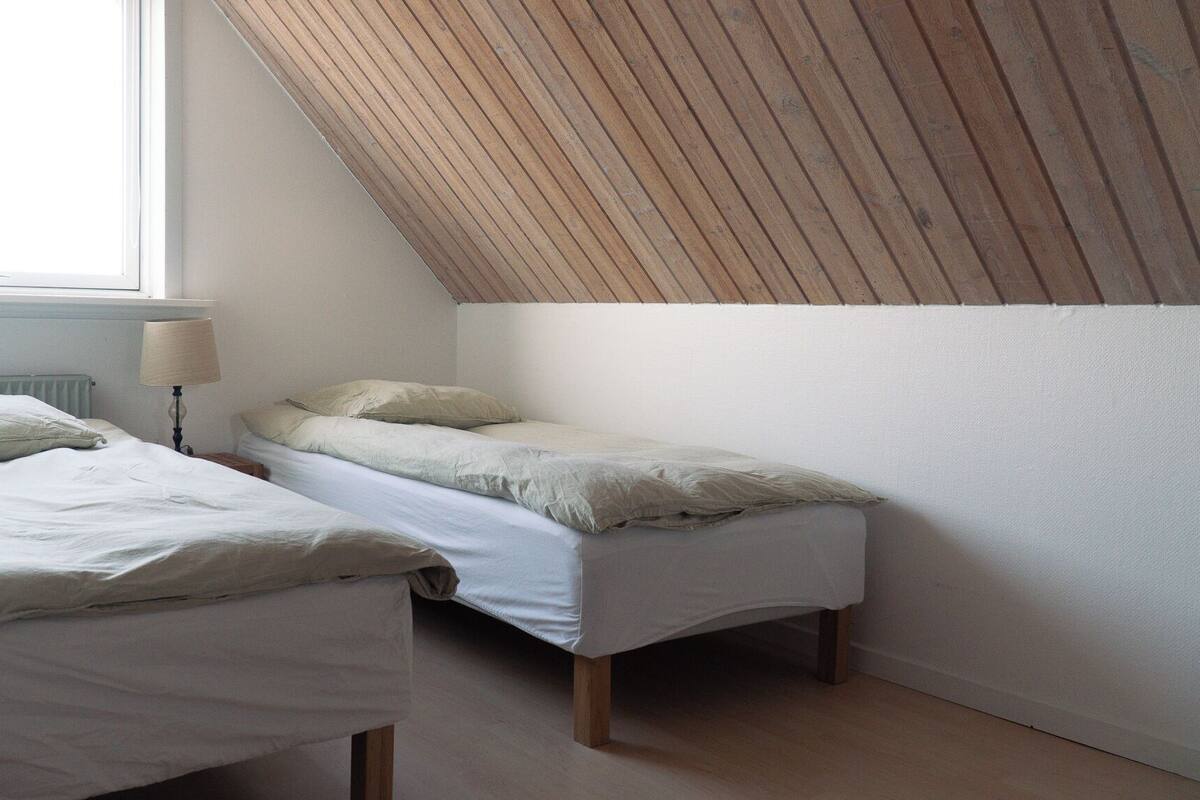 A small, simple room with two beds, a radiator, and a sloped ceiling.