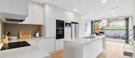 A modern kitchen with a central island, built-in appliances, and a view to an outdoor patio area.