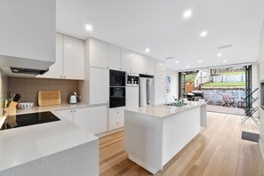 A modern kitchen with a central island, built-in appliances, and a view to an outdoor patio area.
