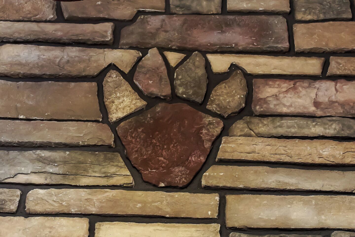A stone wall with a carved paw print design.