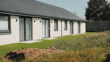 A modern house with a long, flat roof, large windows, and a well-maintained lawn.