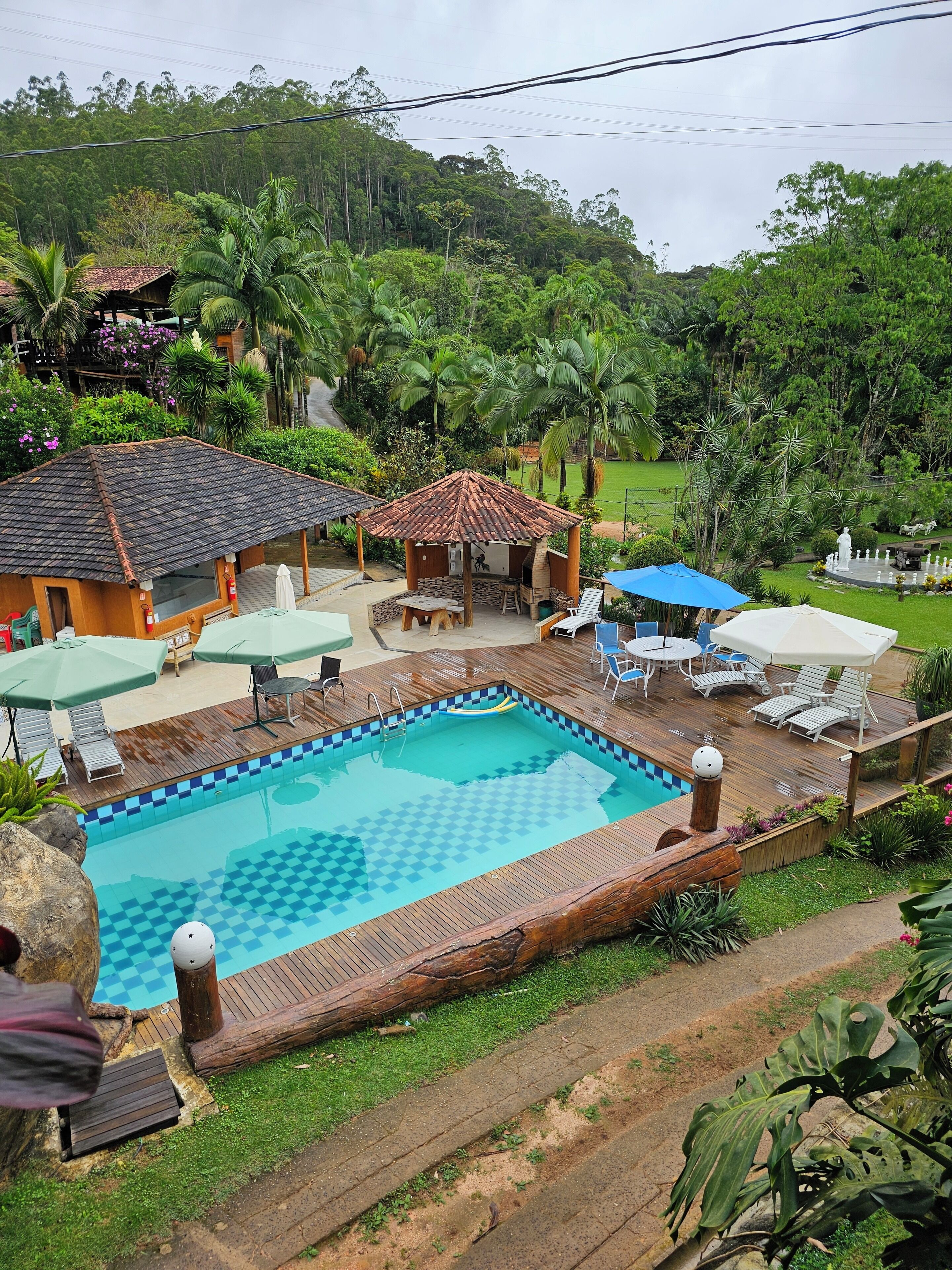 A pool area with a wooden deck, lounge chairs, and a gazebo.