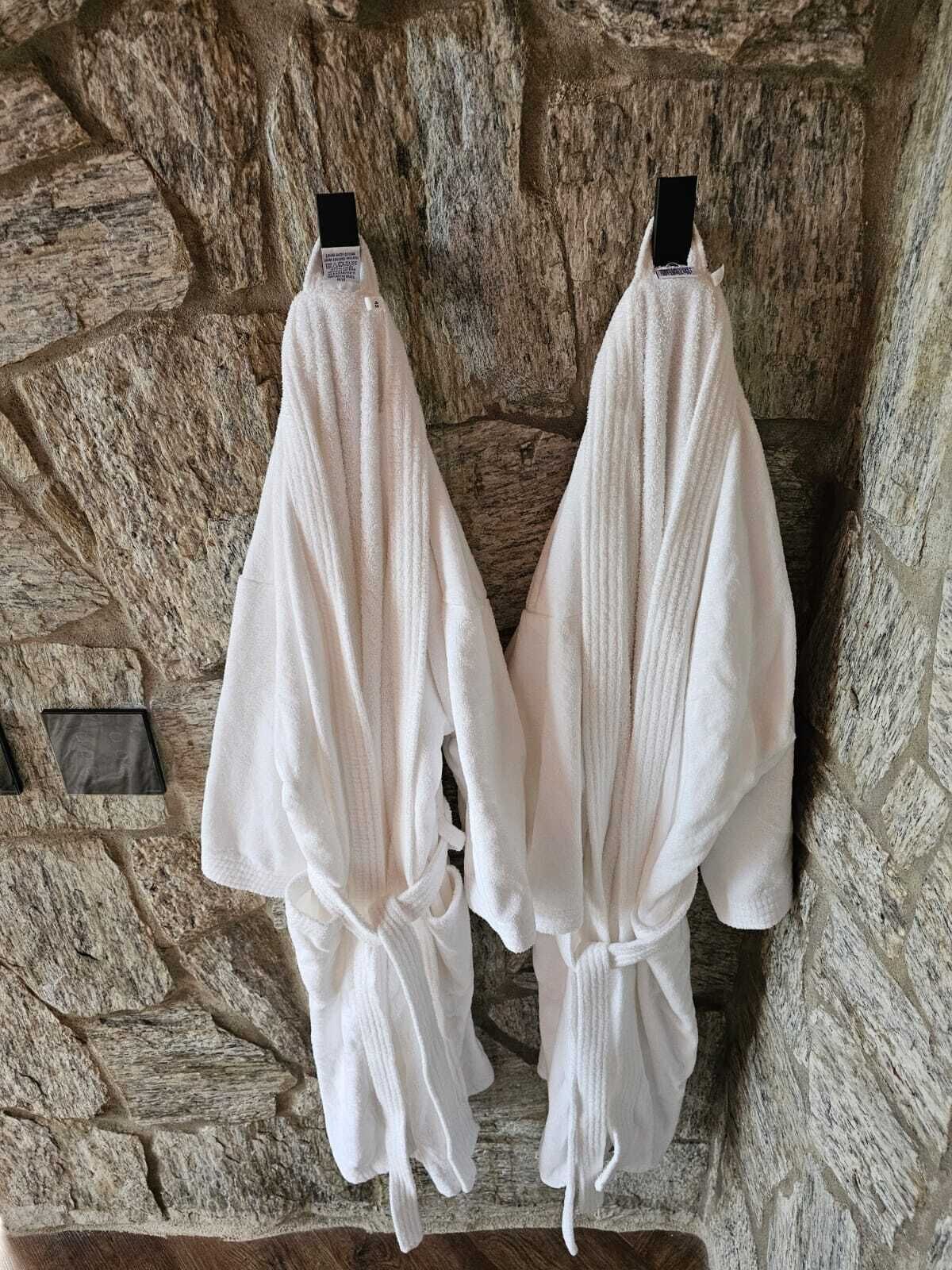 Dos túnicas blancas colgadas en una pared de piedra.