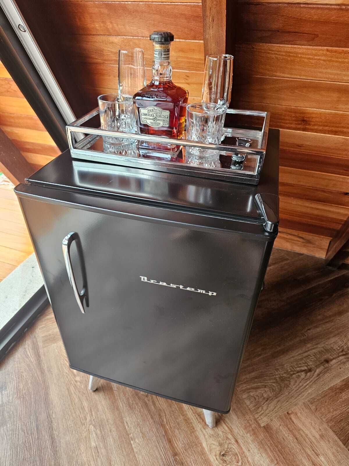 Ein kompakter, schwarzer Kühlschrank mit integrierter Bar, inklusive Flasche und Gläsern.