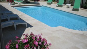 A swimming pool with lounge chairs and a flower bed.