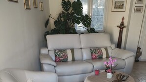 A living room with a sofa, a coffee table, and a large plant.