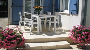 A patio with a table and chairs, a potted plant, and a blue door.